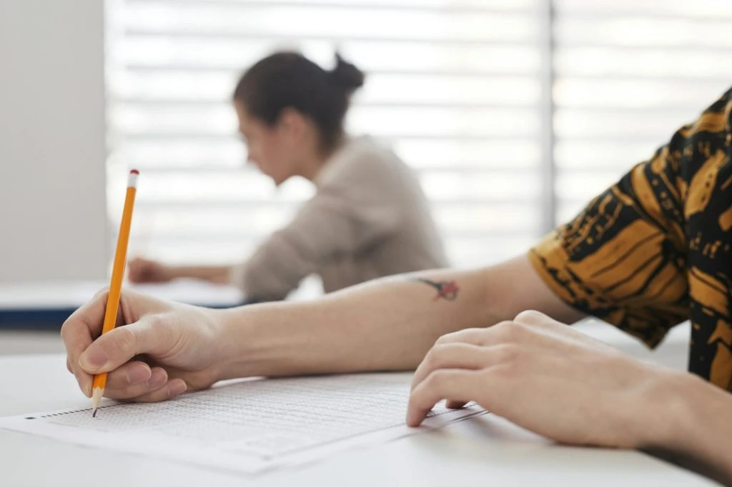 a person writing on a paper using pencil